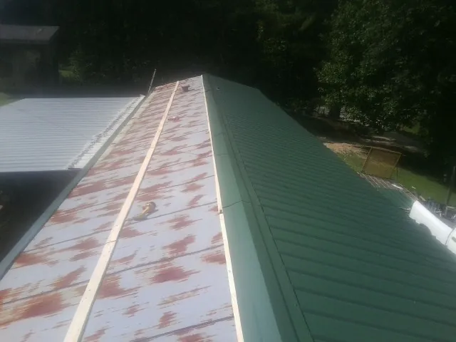 Old rusted panels beside newly installed green metal roofing — Wind Damage Roof Repair by Roofing Brothers in Patrick Air Force Base