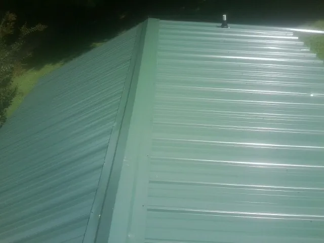 New green metal panels meeting at the ridge of a roof — Flat Roof Repair work by our crew in Patrick Air Force Base