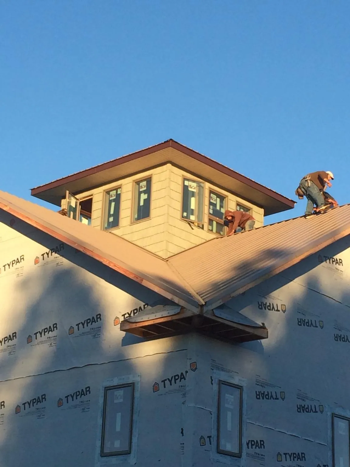 Roofers working around a rooftop cupola on a new metal roof at sunset — Roof Waterproofing in Patrick Air Force Base by Roofing Brothers